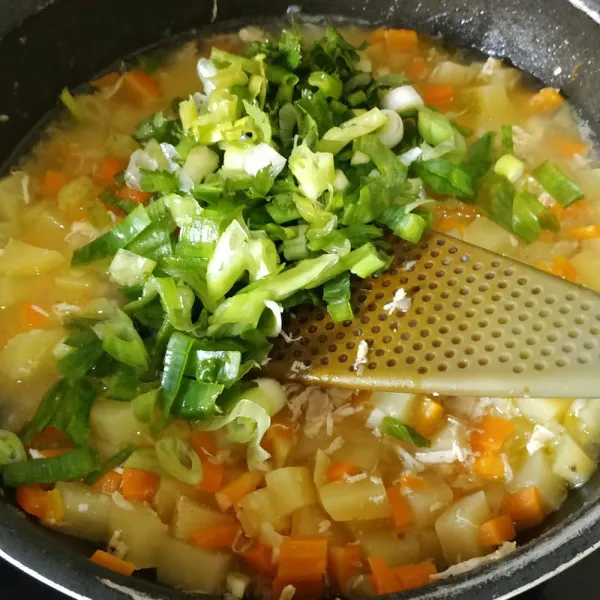 Saat wortel dan kentang sudah hampir lunak, tambahkan daun bawang. Masak hingga air menyusut.