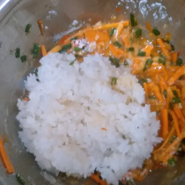 Dalam wadah masukkan wortel, daun bawang, telur, dan nasi aduk sambil nasinya dihancurkan sampai semua tercampur rata.