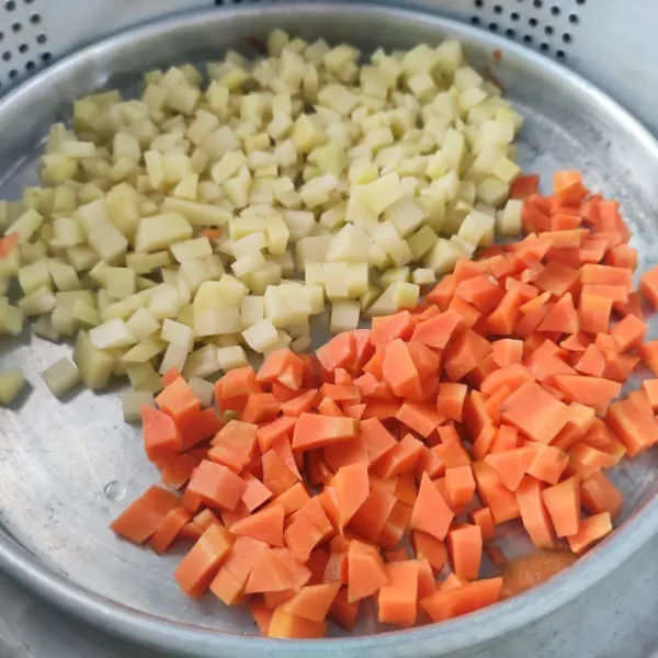 Kupas, cuci bersih, dan potong dadu kecil kentang dan wortel. Kemudian kukus sekitar 10 menit, angkat dan sisihkan.
