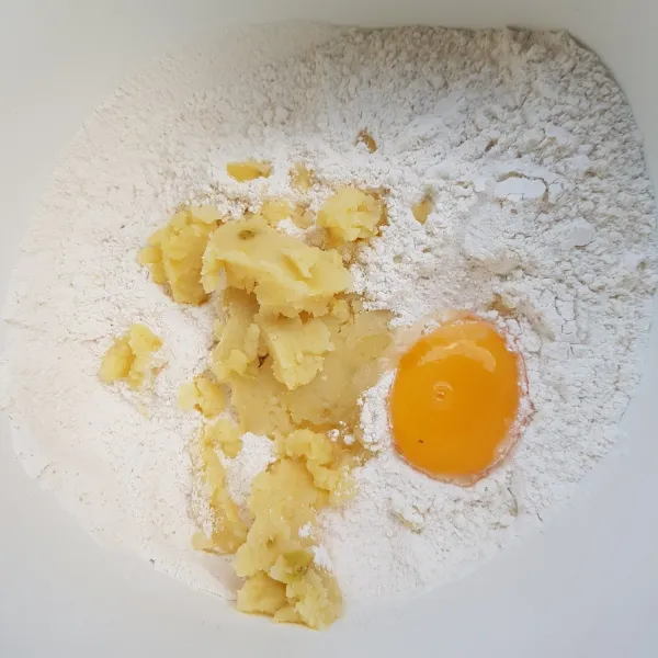 Masukkan kentang kukus yang sudah dihaluskan, kuning telur dan air sedikit demi sedikit. Uleni hingga tercampur rata.
