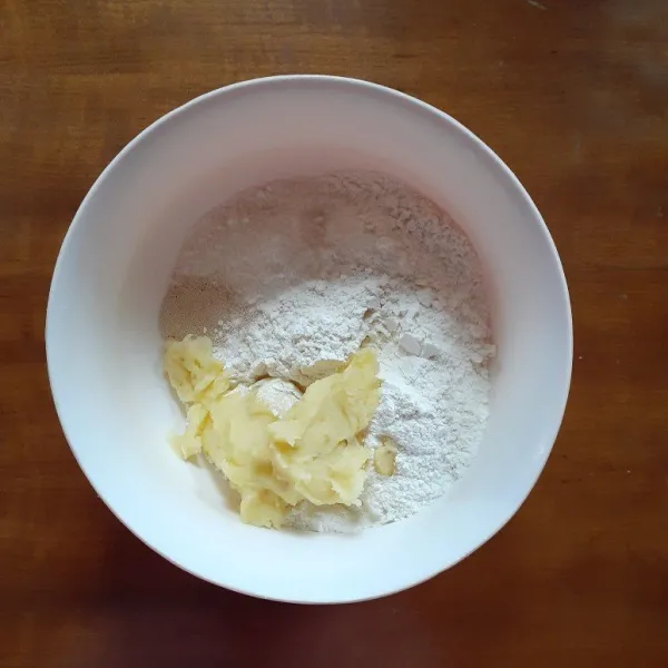 Dalam wadah, campur tepung, susu bubuk, gula pasir, aduk merata. Masukkan pula kentang halusnya, Uleni mereta.