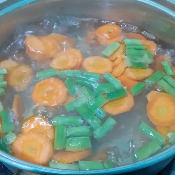 Rebus wortel dan buncis bersama air hingga mendidih dan sayuran agak layu.