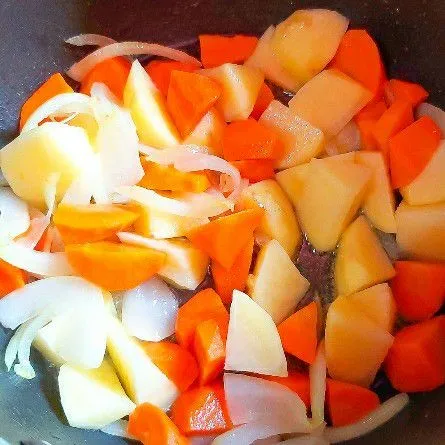 Panaskan minyak lalu tumis 1/2 bagian bawang bombay. Bila sudah harum masukan wortel. Tumis sampai mulai berubah warna lalu masukkan kentang. Tuang kaldu ayam rebus dengan api sedang sampai setengah empuk.