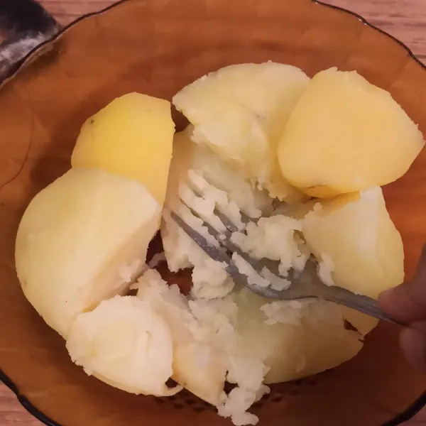 Kupas kulit kentang, lalu tumbuk kentang selagi masih panas.