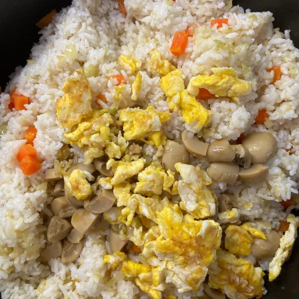 Tambahkan telur yang sudah dimasak dan jamur yang sudah ditumis ke teflon berisi nasi
