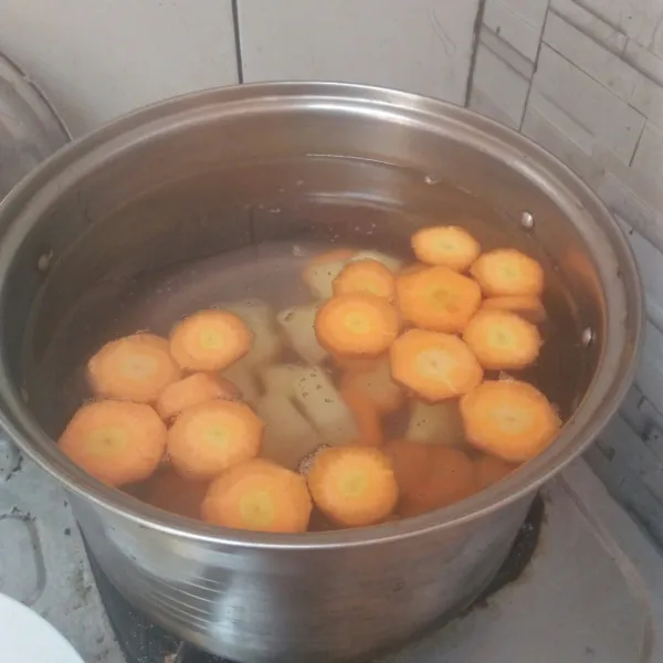 Didihkan air di panci lalu masukan wortel dan kentangnya.