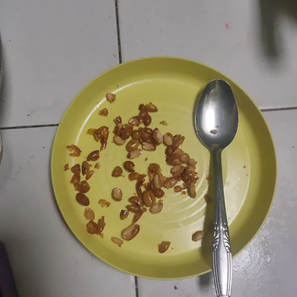 Ambil kacang goreng tekan-tekan menggunakan sendok agar terbelah. Kupas agar kulitnya terbuang. Taburkan di atas tumisan yang siap disajikan.