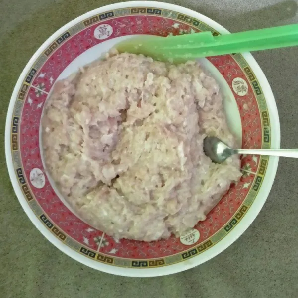 Untuk isi, siapkan baskom, masukkan ayam giling, tepung tapioka, bawang putih halus, garam, dan lada bubuk. Aduk rata