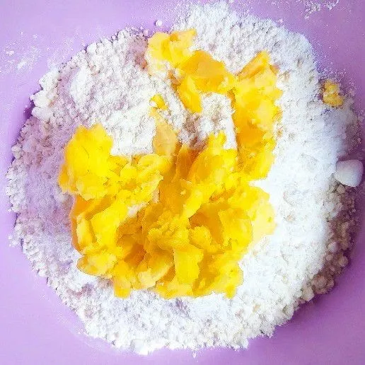 Campurkan tepung, gula, mentega dan margarin dengan spatula. Hindari menggunakan tangan kosong karena akan membuat mentega dan margarin cepat leleh. Aduk hingga berpasir. Lalu masukkan kuning telur dan aduk rata kembali.