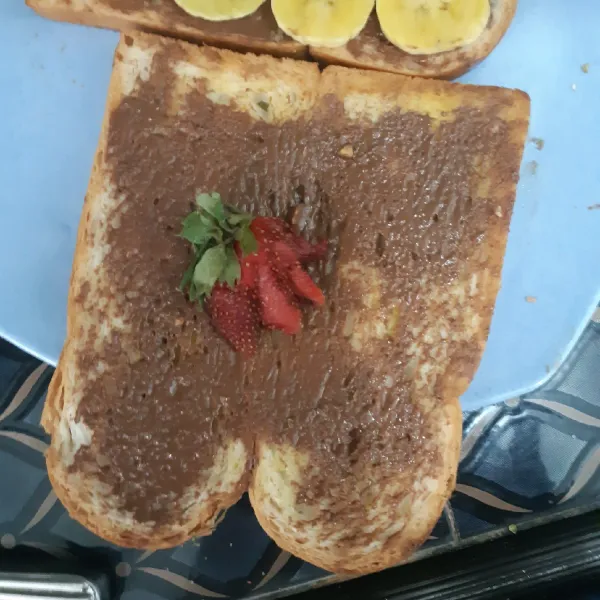 Beri buah strawberry untuk roti satunya, siap dinikmati