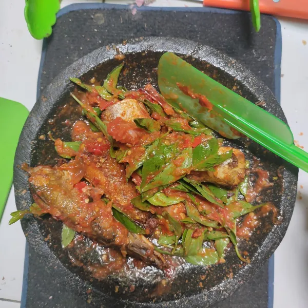 Ulek bumbu sambal yang sudah digoreng. Tambahkan garam, gula, dan terasi. Koreksi rasa. Lalu tambahkan kemangi beserta ikan, aduk merata dan sajikan.