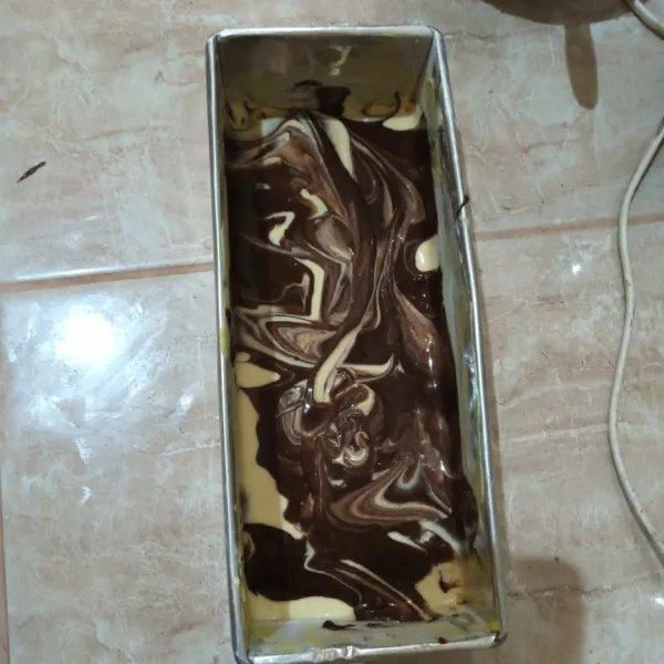 Olesi loyang dengan blueband dan taburi terigu. Kemudian tuang adonan putih terlebih dahulu, tuang lagi adonan cokelat. Oven suhu 180°C selama 35 menit