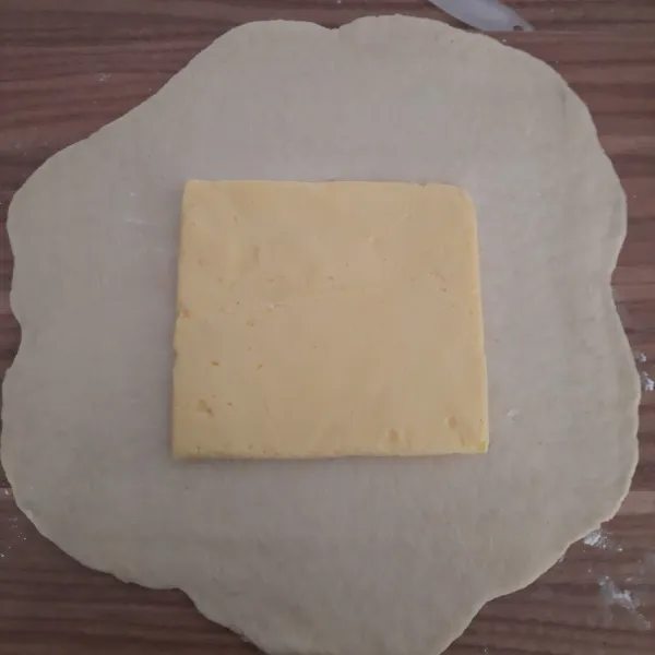 Giling adonan utama melebar, lalu letakkan butter dtengahnya.
