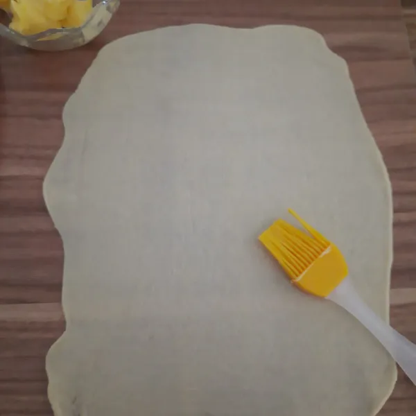 Giling adonan hingga tipis sekali, oles dengan butter seluruh permukaan.