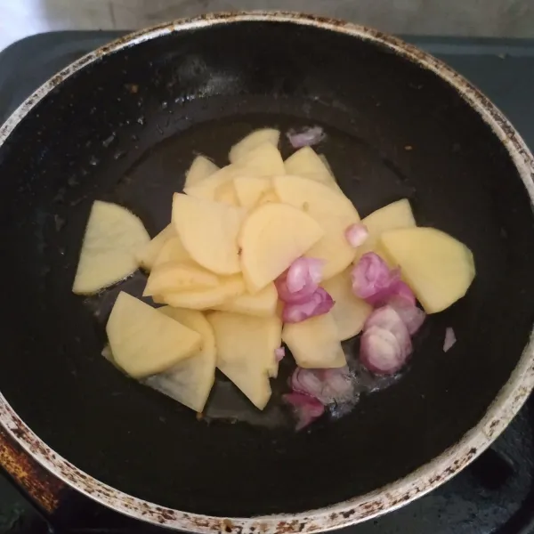 Goreng kentang dan bawang merah sampai setengah matang.