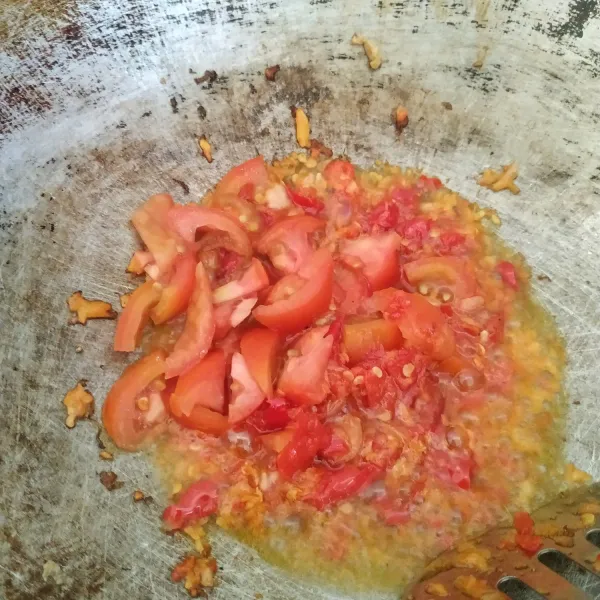 Tumis bumbu halus sampai harum. Masukkan irisan tomat, aduk rata.