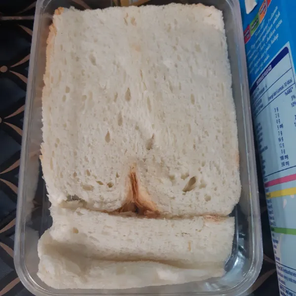 Potong pinggiran roti tawar kemudian susun ke dalam wadah