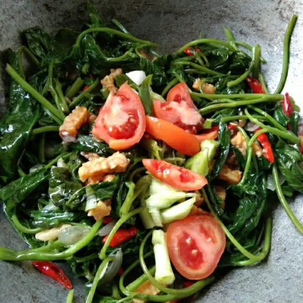 Tambahkan irisan tomat dan bawang daun, masak hingga matang