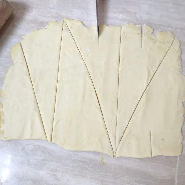 Selanjutnya adonan dipotong menjadi 6 bagian membentuk segitiga siku-siku, kerat sedikit bagian ujungnya agar mudah digulung.