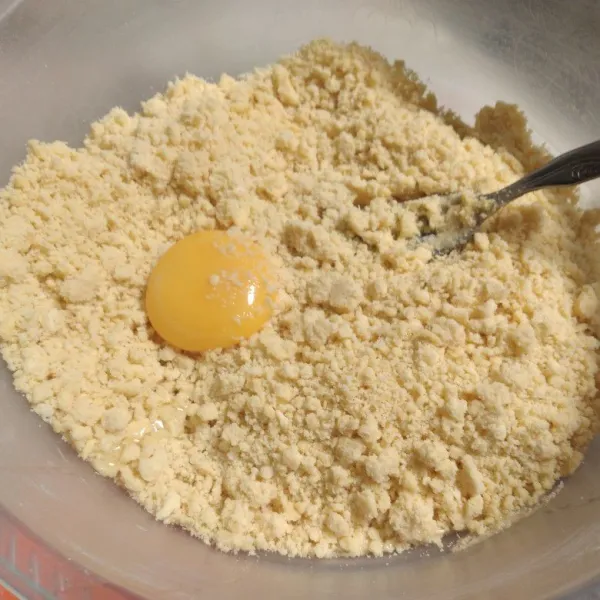 Masukkan kuning telur, uleni hingga tercampur rata sambil diberi sedikit demi sedikit air es, uleni hingga rata.