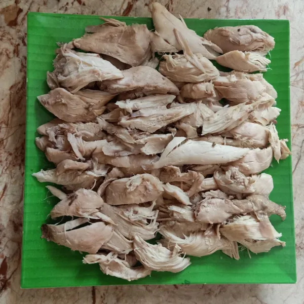 Suwir-suwir daging ayam kampung yang sudah matang dan disusun rapi di atas piring