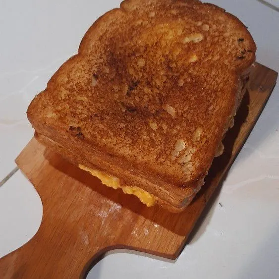 Lalu angkat sandwich yang sudah di toast, setelah itu di potong jadi 2 bagian.