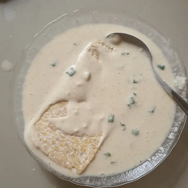Ambil satu lembar tempe yang telah diiris tipis, masukkan ke dalam adonan tepung.