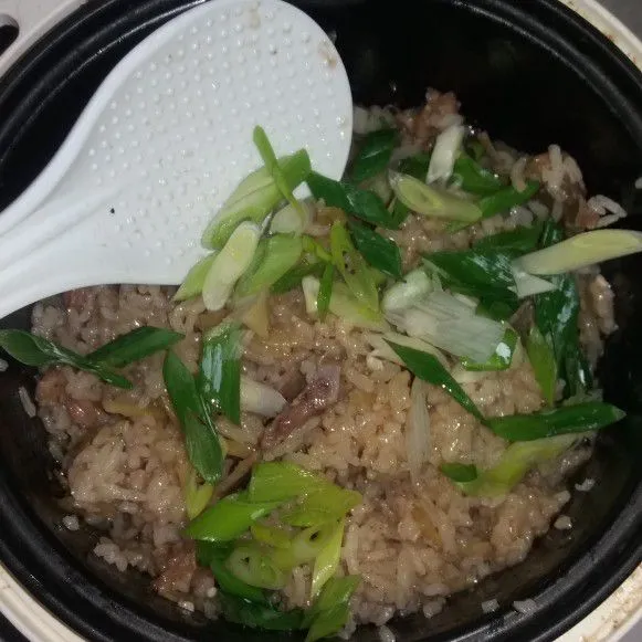 Aduk nasi yang sudah matang dan tambahkan bawang daun. Sajikan.