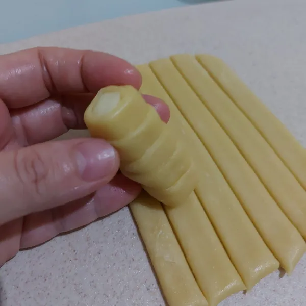 Ambil potongan adonan, lilit keju dengan adonan sampai menutup seluruh bagian. Lakukan sampai selesai.