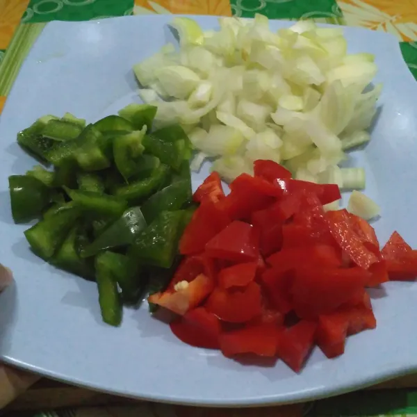 Potong-potong bawang bombay, paprika hijau, dan merah.