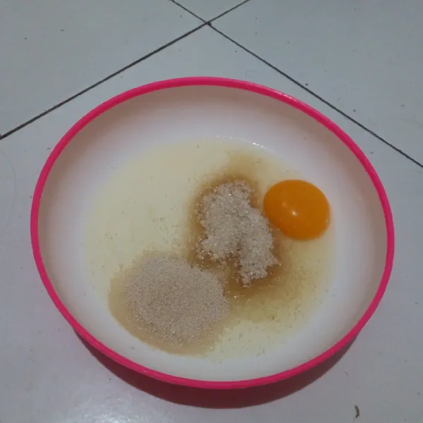 Dalam wadah, masukkan telur, gula pasir, dan ragi instan. Kocok menggunakan garpu.