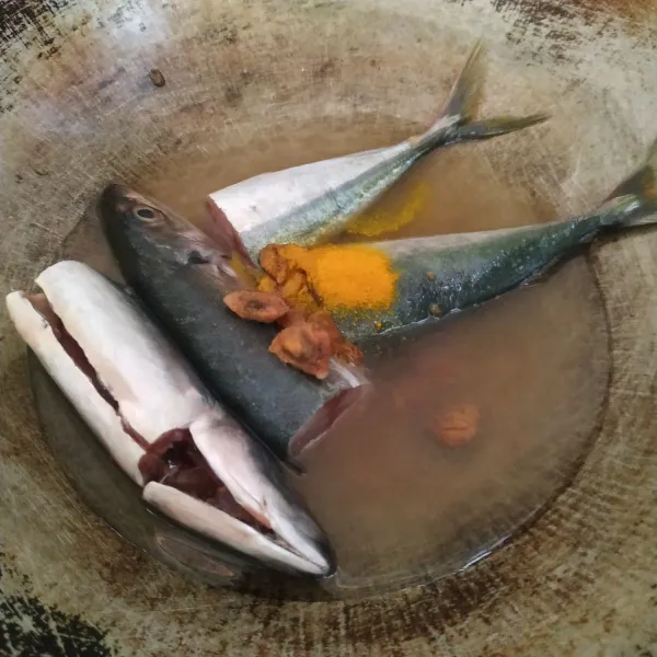 Masukkan ikan lajang, air asam jawa, dan kunyit ke dalam wajan.