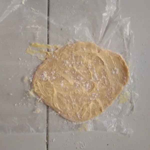 Pipihkan adonan dan olesi margarin setelah itu taburi tepung terigu protein tinggi.
