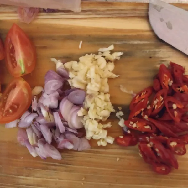 Iris-iris bawang putih dan bawang merah. Cabe merah besar iris serong dan tomat belah jadi 4.