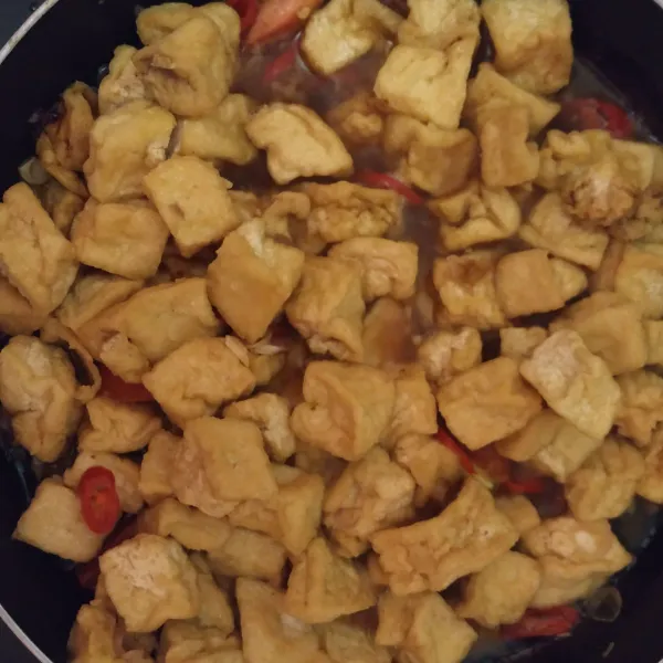 Lalu masukkan tahu yang sudah digoreng tadi. Tambahkan juga bumbu, cabe merah besar, air dan kecambah. Aduk rata sampai matang lalu angkat dan sajikan.