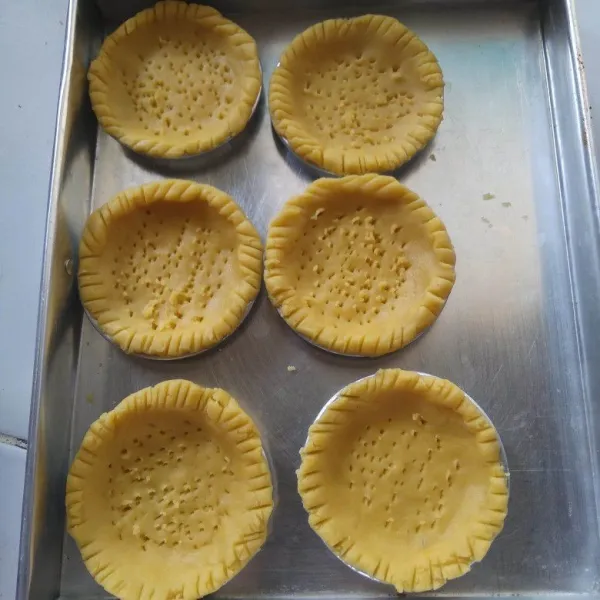 Ambil sedikit adonan, pipihkan pada cetakan pie yang sudah diolesi margarin. tusuk bagian tengahnya dengan garpu dan kerat sisinya dengan pinggiran sendok.