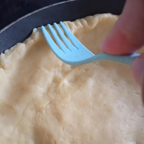 Siapkan wajan teflon, olesi tipis margarin dipermukaannya, lalu bentuk/ratakan adonan di dalam wajan, beri pola di pinggiran crust menggunakan garpu.