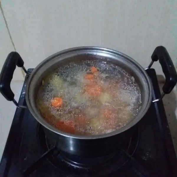 Tumis bawang merah dan bawang putih halus hingga harum. Masukan air, wortel dan kentang. Rebus hingga mendidih dan sayuran matang.