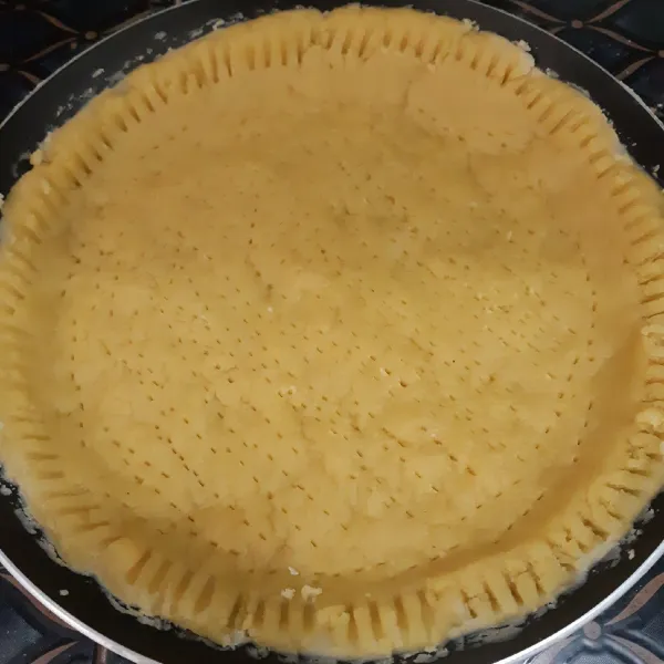 Pipihkan adonan kuliat pie secara merata di teflon, kemudian tusuk-tusuk permukaan kulit pie menggunakan garpu