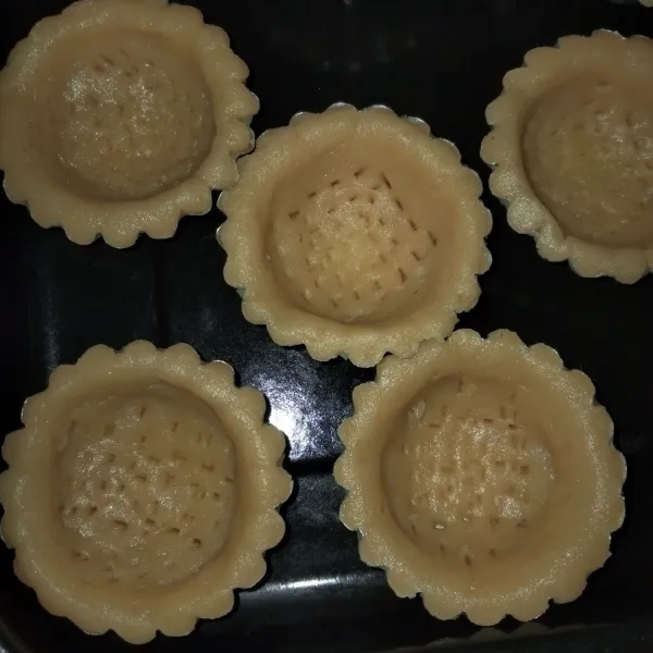 Siapkan cetakan pie yang sebelumnya sudah di olesi margarin bentuk adonan pie hingga rata menutupi cetakan lalu di tusuk dengan garpu supaya di mengembang saat di panggang, sisihkan.