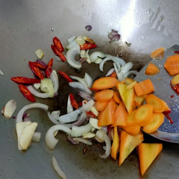 Masukkan wortel yang sudah diiris tipis, tumis hingga wortel setengah matang.