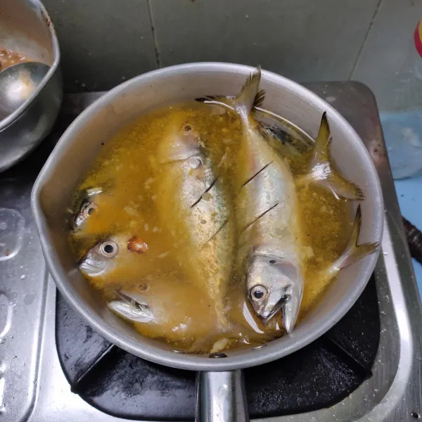 Masukkan bumbu ke dalam panci, beri air dan garam. Tata ikan. Masak hingga mendidih dan matikan. Biarkan dingin lalu goreng hingga garing.