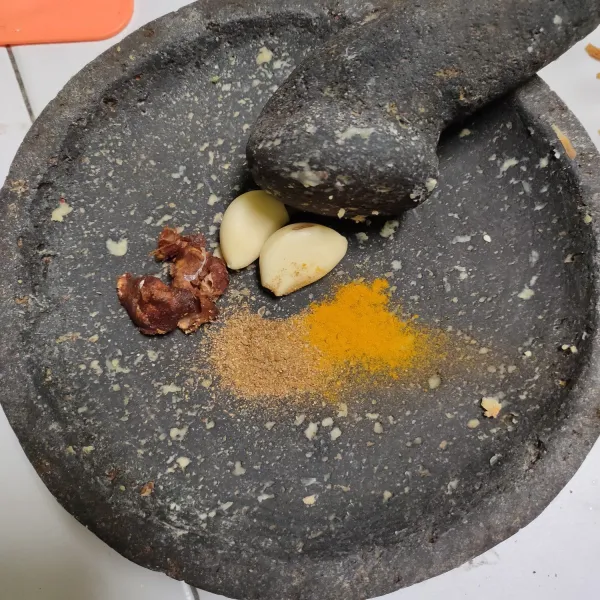 Ulek halus bawang putih, asam, ketumbar bubuk, dan kunyit bubuk.