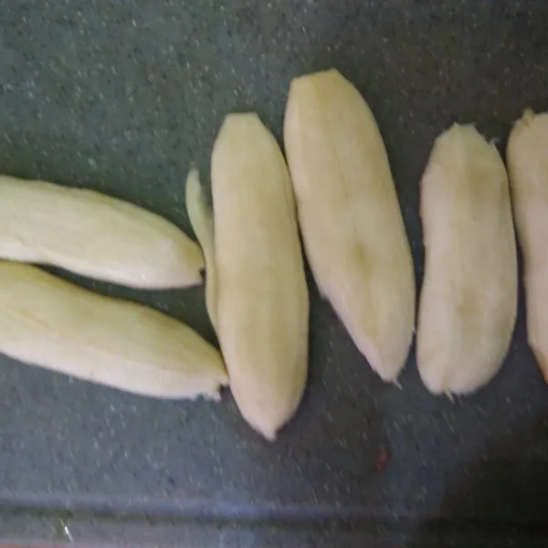 Kupas pisang dan belah menjadi 2 bagian.
