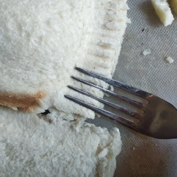 Lipat roti tawar, kemudian rekatkan ujungnya dengan menggunakan garpu.