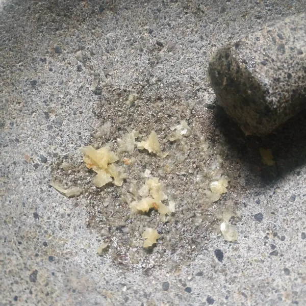 Haluskan bawang putih dengan ulekan.