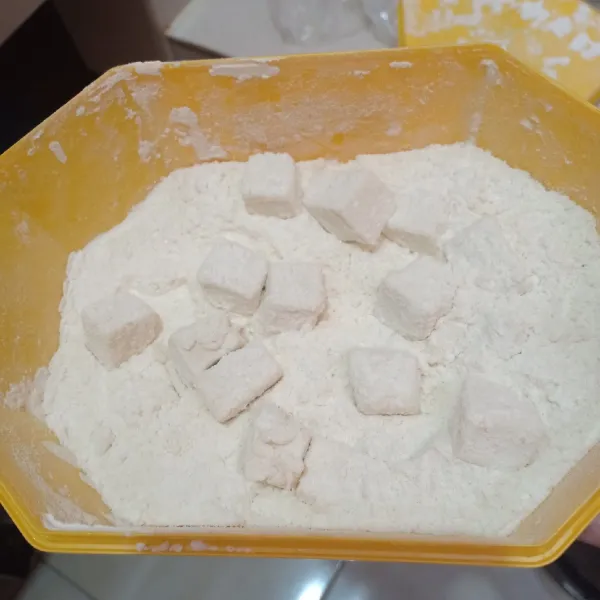 Masukkan potongan tahu ke dalam wadah tepung kering lalu tutup dan kocok hingga terbalur sempurna.