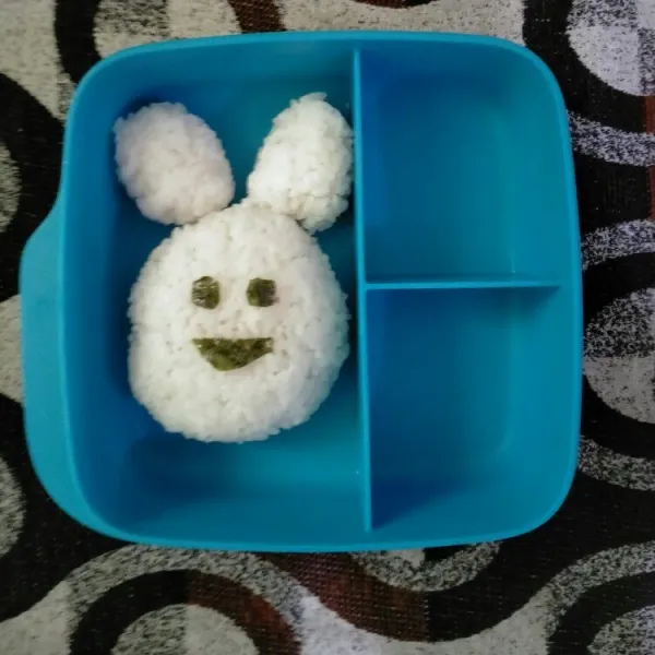 Kepal nasi menjadi bentuk karakter kelinci. Kemudian tambahkan rumput laut sebagai mata dan hidungnya