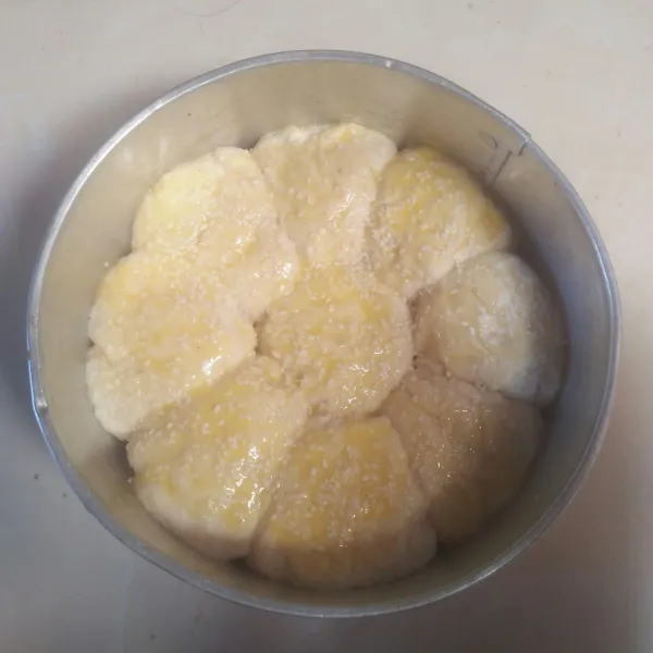 Campurkan bahan olesan lalu oleskan ke bagian atas adonan dengan kuning telur dan kental manis lalu taburi dengan wijen.