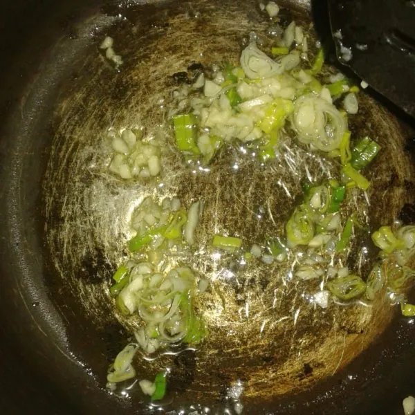 Dalam wadah panci, panaskan minyak, lalu tumis bawang putih dan daun bawang sampai harum.
